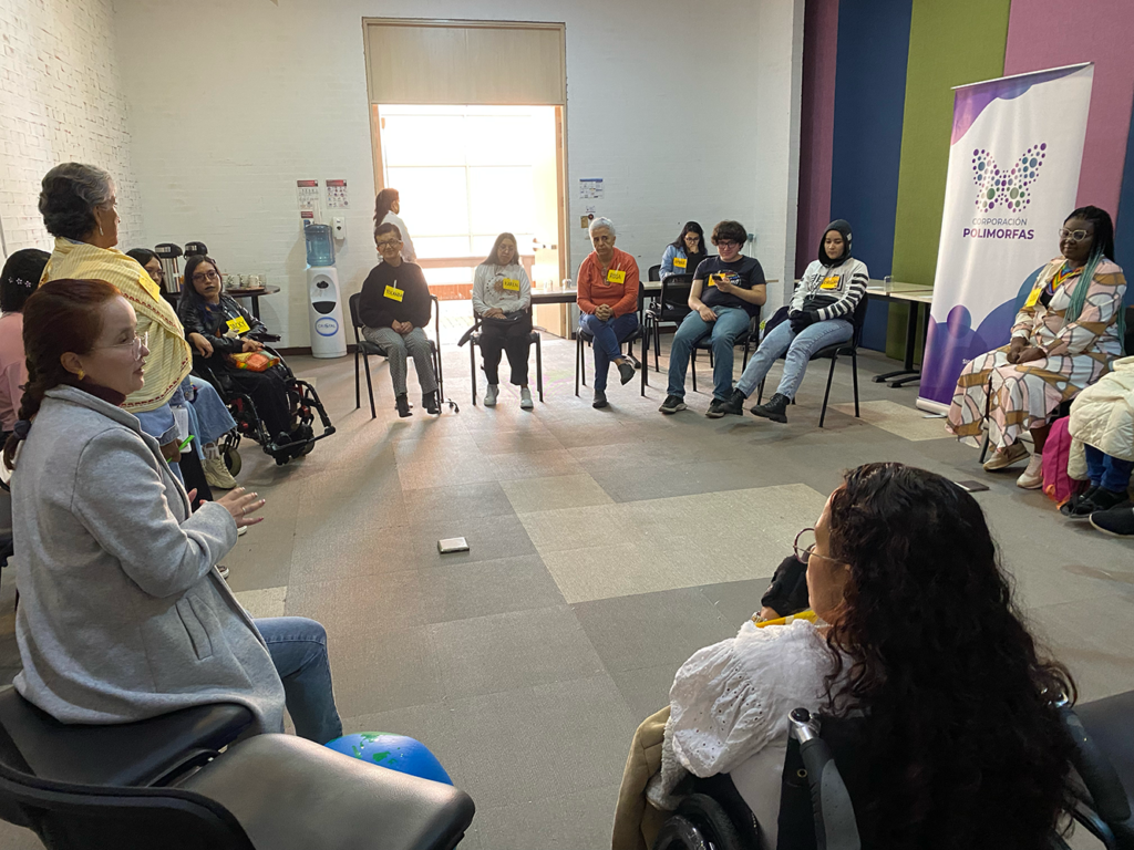 Grupo de mujeres con discapacidad en semicírculo dialogando durante la actividad “El tendedero”