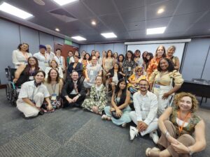 Fotografía grupal en la que aparecen 33 personas diversas, entre ellas mujeres con discapacidades físicas, auditivas, visuales en un recinto cerrado.